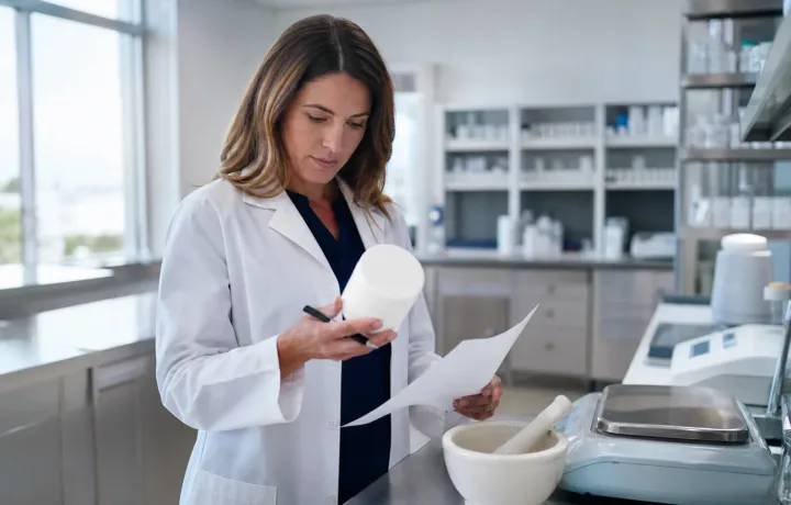 Pharmacist reviewing compounding ingredients and quality records in a community pharmacy