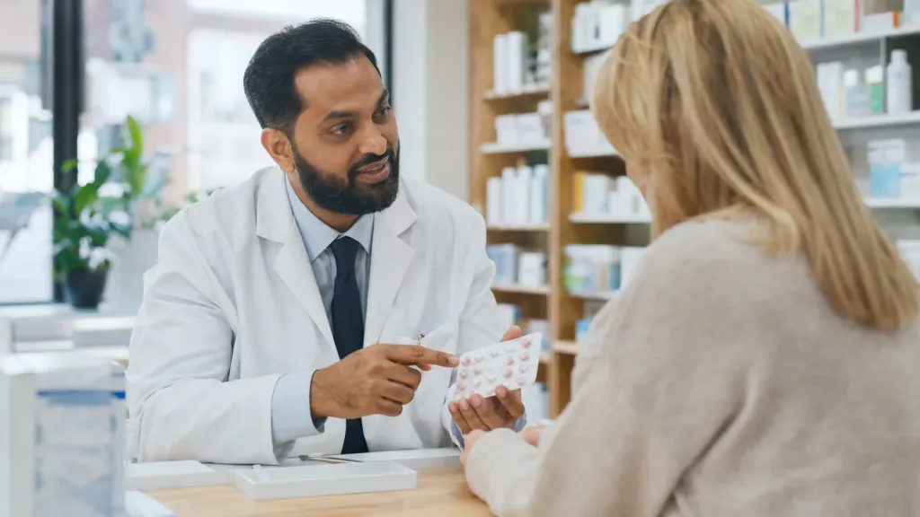 Pharmacist helping a patient with a medication communication question in a community pharmacy