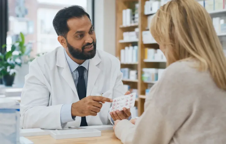 Pharmacist helping a patient with a medication communication question in a community pharmacy