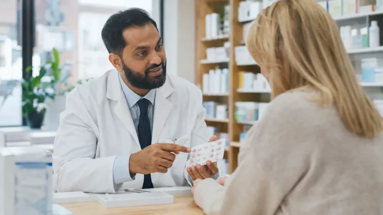 Pharmacist helping a patient with a medication communication question in a community pharmacy